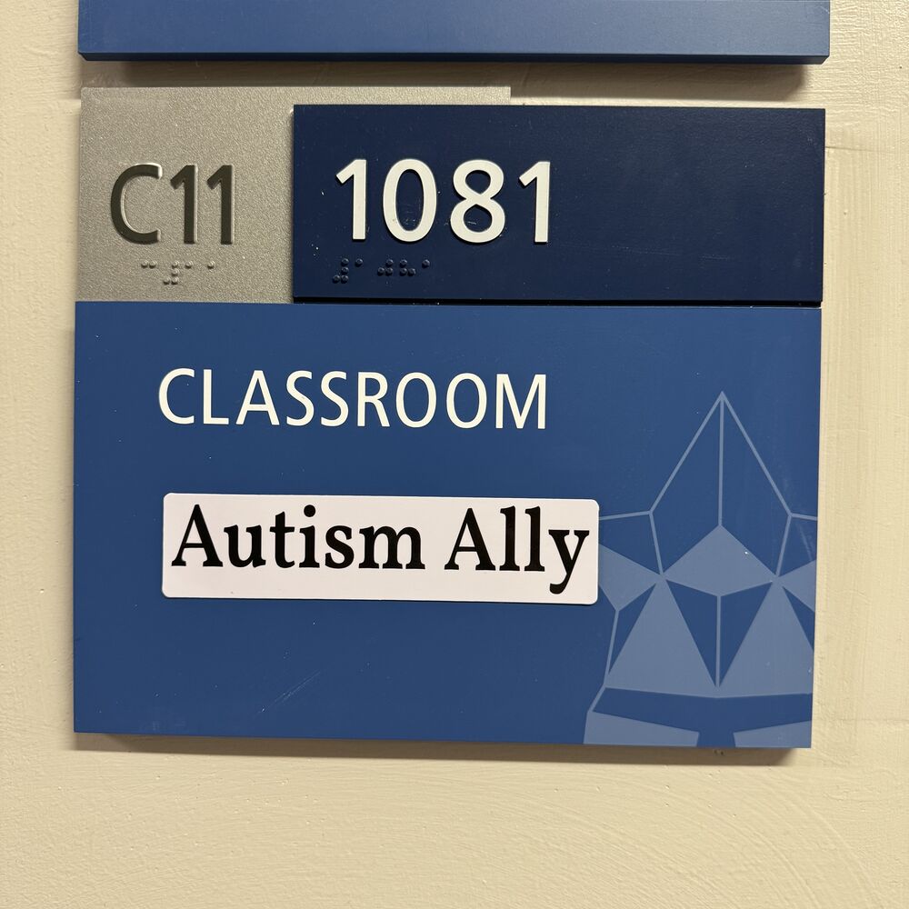 The Autism Ally sticker on a school classroom door sign.