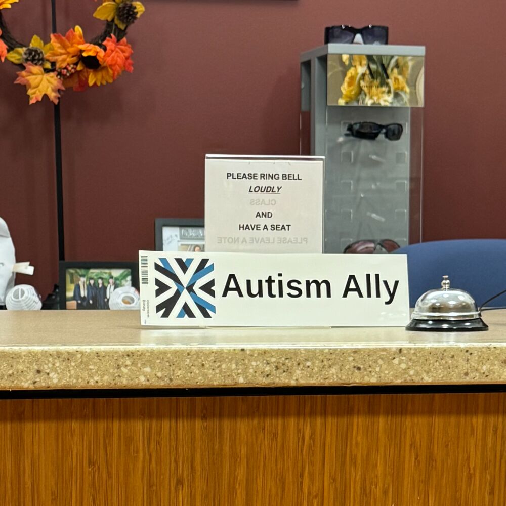 The Autism Ally sticker on the reception counter of an optometry office.