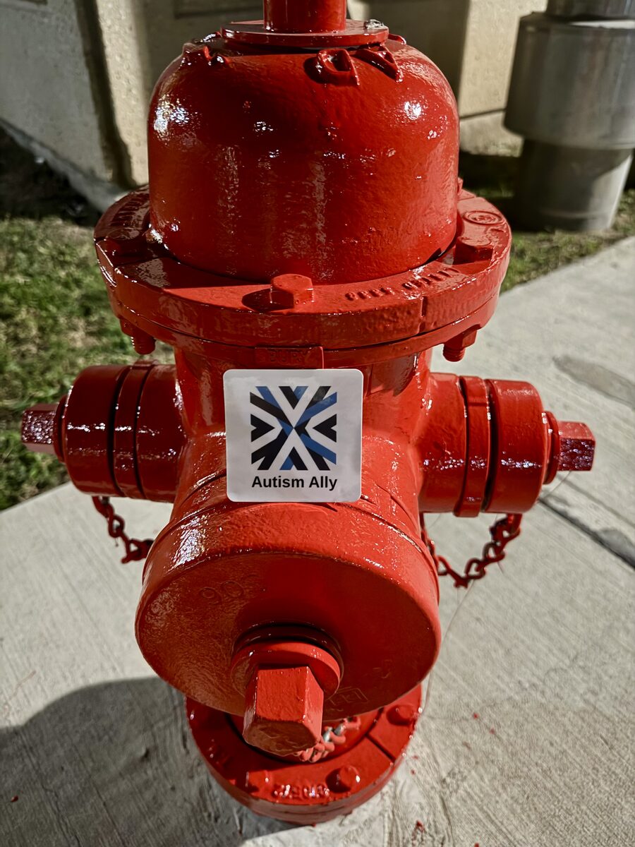 The Autism Ally sticker on a red fire hydrant.